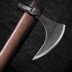 Detailansicht der Wikinger-Axt MJÖLNIR mit geschwungener, geschmiedeter Stahlklinge und dunklem Holzstiel auf Stein-Hintergrund