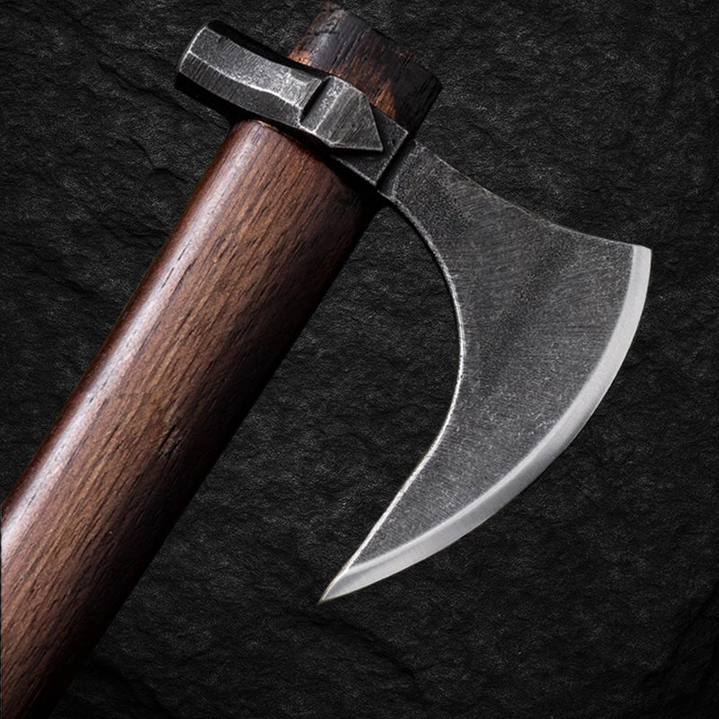 Detailansicht der Wikinger-Axt MJÖLNIR mit geschwungener, geschmiedeter Stahlklinge und dunklem Holzstiel auf Stein-Hintergrund