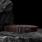 Echtleder-Gürtel aus braunem Rindsleder flach liegend auf schwarzem Steinfelsen – Lochung sichtbar