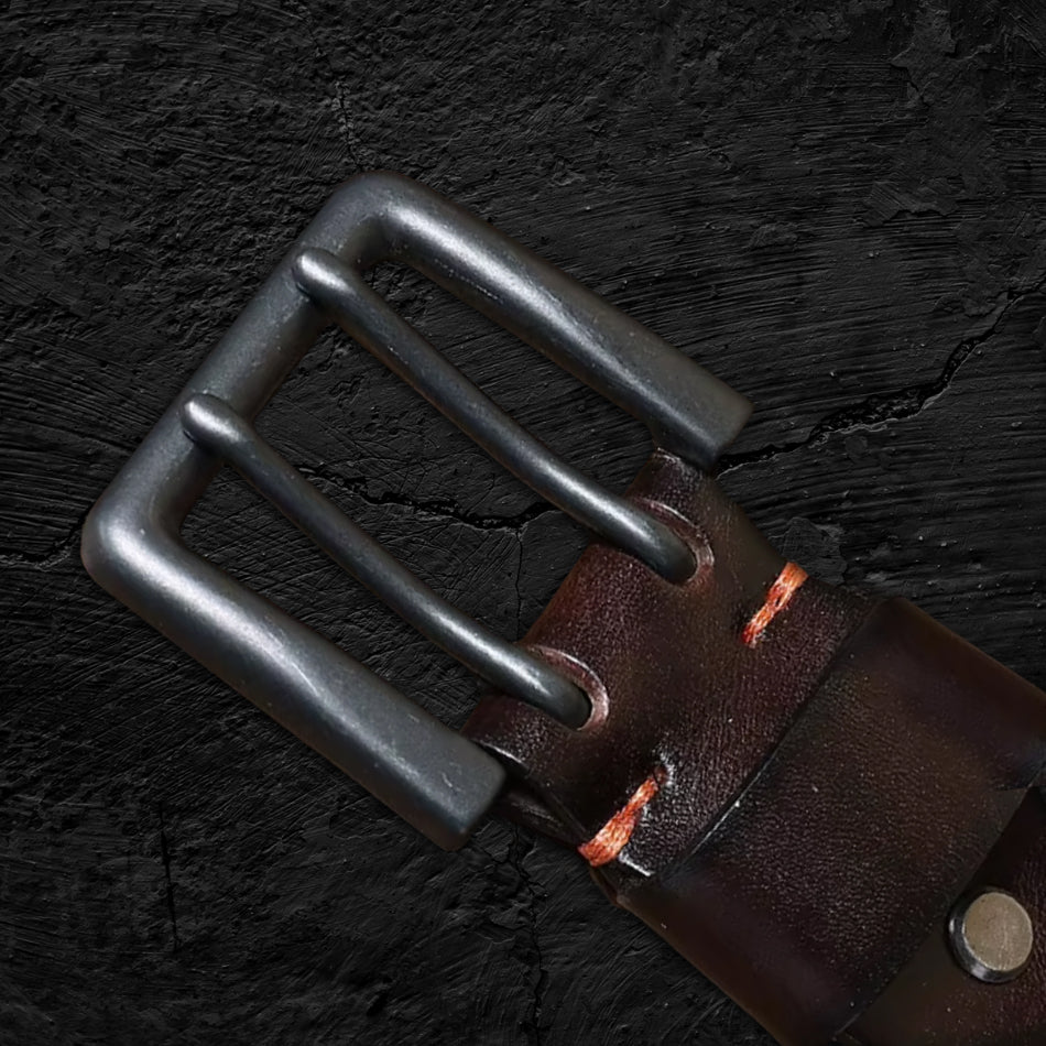 Echtleder-Gürtel aus braunem Rindsleder auf schwarzem Steinfelsen – Detailaufnahme der Schnalle