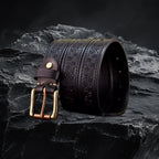 Echtleder-Gurt für Herren in Black– gerollt mit Metallschnalle auf schwarzem Steinfelsen