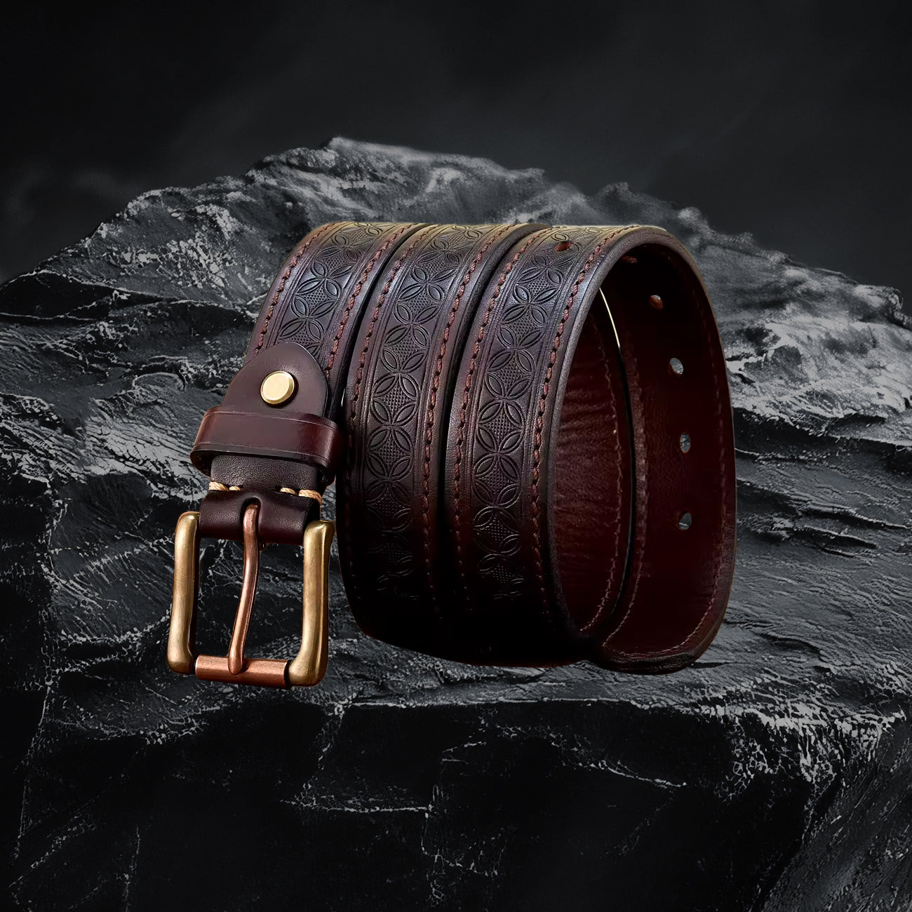 Echtleder-Gurt für Herren in Coffee – gerollt mit Metallschnalle auf schwarzem Steinfelsen