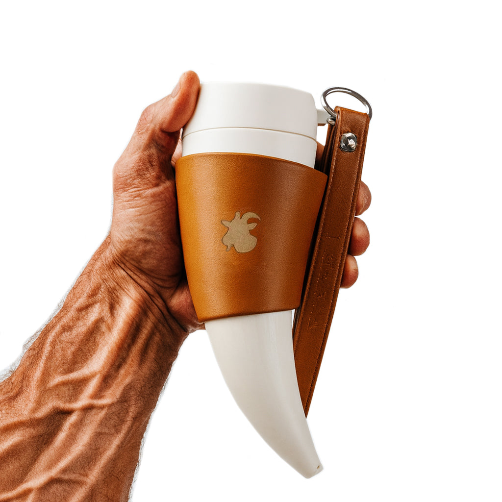 Weisser Thermobecher im Wikinger-Horn-Design mit braunem Lederhalter, in muskulöser Wikinger-Hand gehalten