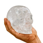 Grosser Kristall-Totenkopf aus echtem Bergkristall (1500–1600 g) – gehalten in kräftiger, leicht verschmutzter Männerhand. Handgeschliffener Kristallschädel, Symbol für Stärke, Klarheit, Energie und nordische Handwerkskunst.