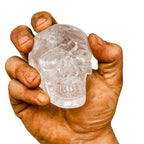 Echter Kristall-Totenkopf aus handgeschliffenem Bergkristall – gehalten in kräftiger, leicht verschmutzter Männerhand. Symbol für Klarheit, Energie, Stärke und nordische Handwerkskunst.