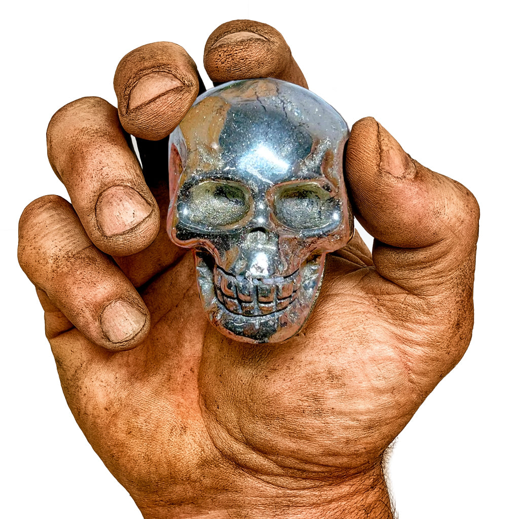 Echter Pyrit-Totenkopf – gehalten in rauer, muskulöser Männerhand. Glänzender Wikinger-Schädel aus Stein, Symbol für Stärke, Mut und Handwerkskunst.
