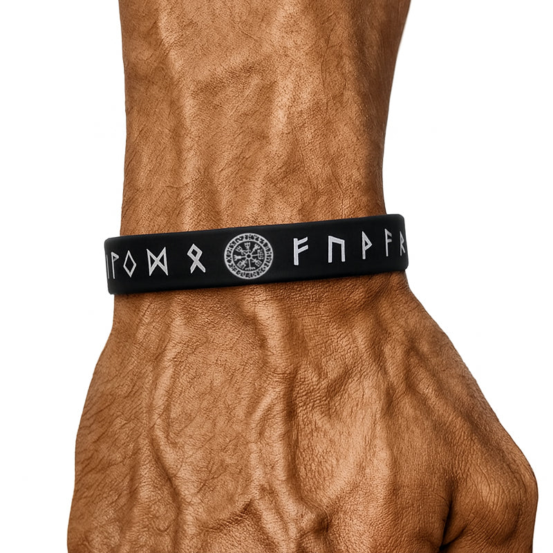 Schwarzes Wikinger-Armband aus Silikon mit weißen Runen und Vegvísir-Symbol, getragen am muskulösen Männerhandgelenk.