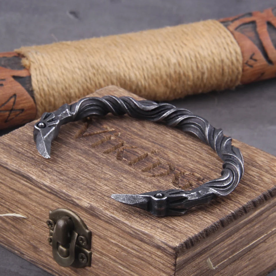 VIKING-OATH Wikinger Armring – detailreiches Raben-Design, fotografiert auf rustikalem Hintergrund