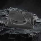 Echtleder Umhängetasche Damen in Schwarz aus echtem Leder auf dunklem Fels-Hintergrund