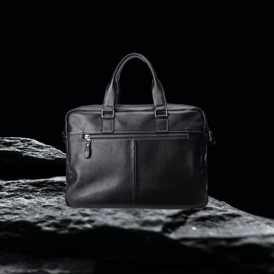 Herren Echtleder Tasche schwarz, langlebige Business Ledertasche aus echtem Leder stehend auf schwarzem Felsen