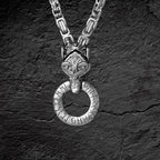 Wikinger Halskette Fenris aus Edelstahl mit Wolfskopf und Runenring auf dunklem Stein